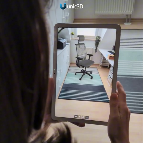 Person holding a tablet showing an office chair placed in a room in AR